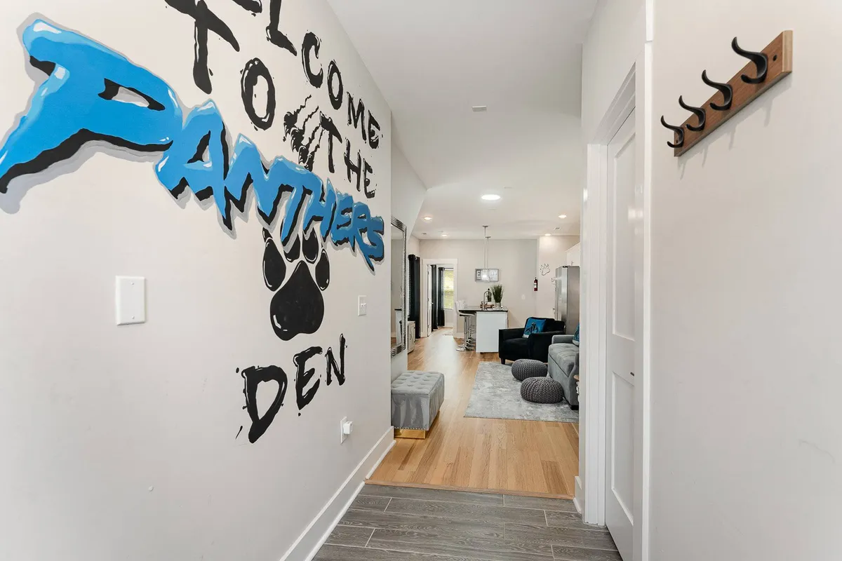 A welcoming lounge area featuring the 'Welcome to the Panthers Den' mural above a comfy seating area and a plush rug, creating a perfect spot for socializing, playing games, or celebrating together.