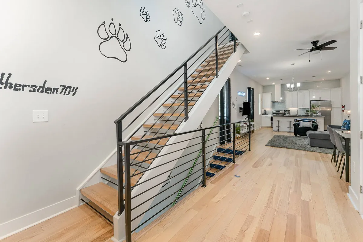 An open living space featuring a staircase, paw print wall decor, and a welcoming area suitable for gatherings. The design suggests a space where multiple groups can interact or enjoy privacy, with visible separation of areas and a friendly, inviting layout.