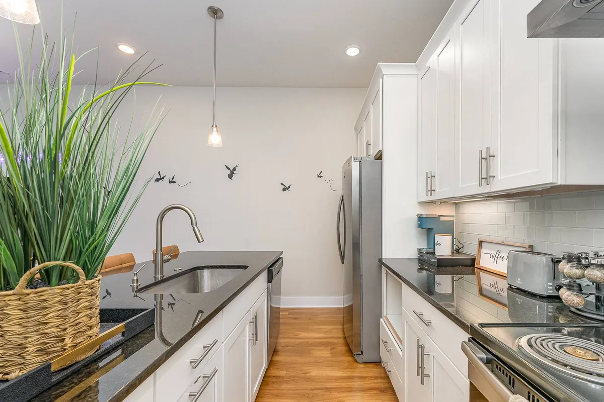 A stylish kitchen with a modern island, stainless steel appliances, a decorative plant, and distinctive bird-themed wall art. The scene exudes a contemporary, inviting feel, reinforcing that multiple kitchens offer both function and flair for any culinary occasion.