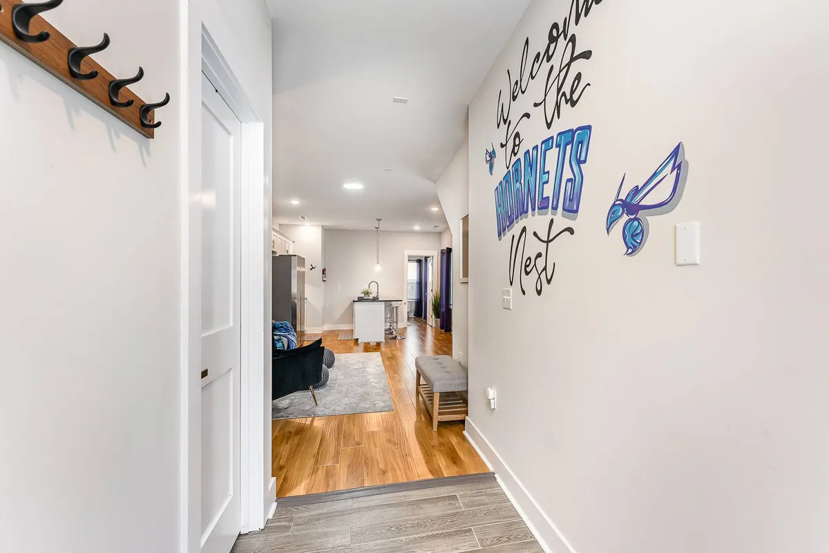 A welcoming entryway with a colorful mural, a bench for greeting guests, and coat hooks. The space feels inviting and vibrant, suggesting the transition from home to city adventures just beyond the door.